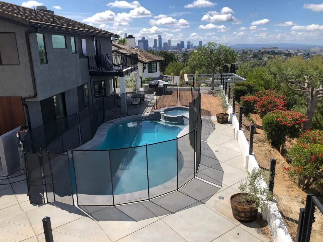 Glendale 1 Freeform pool and spa with a mesh safety fence on a hillside lot overlooking the city