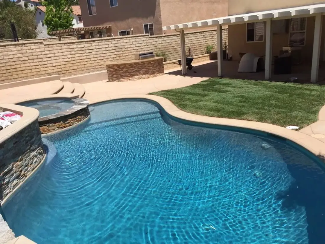 Freeform pool with a stacked-stone raised spa and new lawn