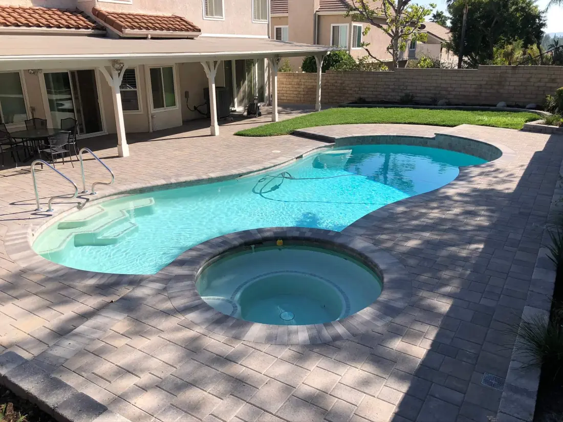 Reseda 1 Freeform pool with an attached round spa and a paver deck