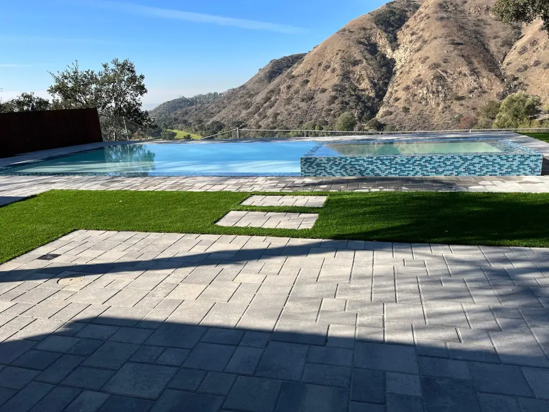 Toluca Lake 2 Infinity-edge pool and glass tile spa with a paver deck and turf below the hills