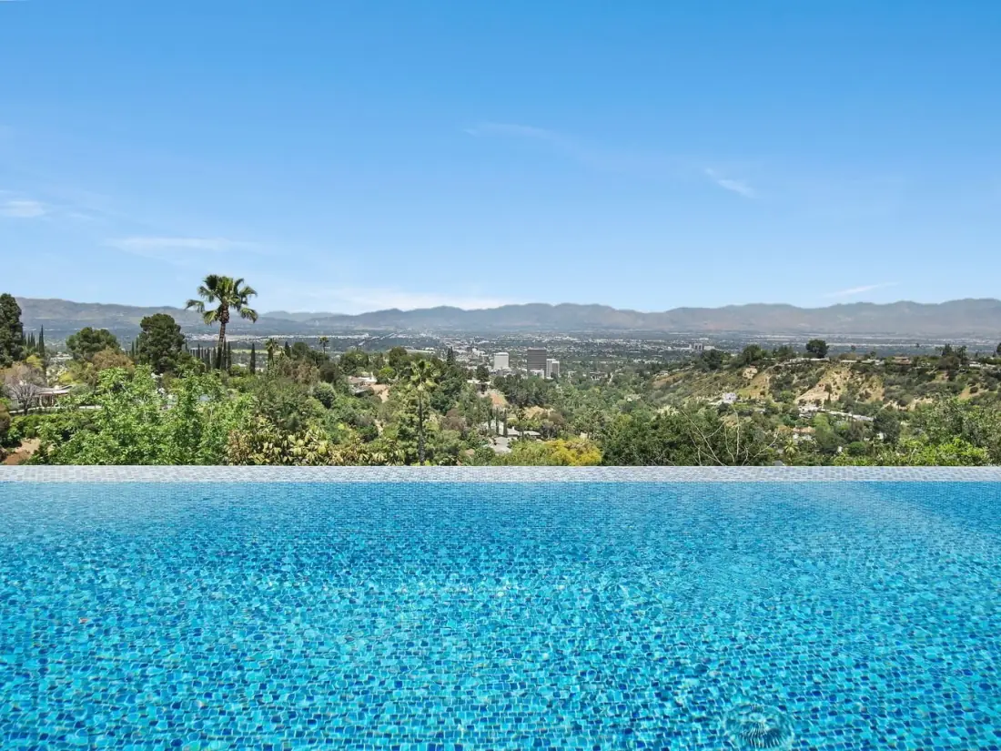 Infinity-edge pool finished in blue mosaic tile overlooking the valley