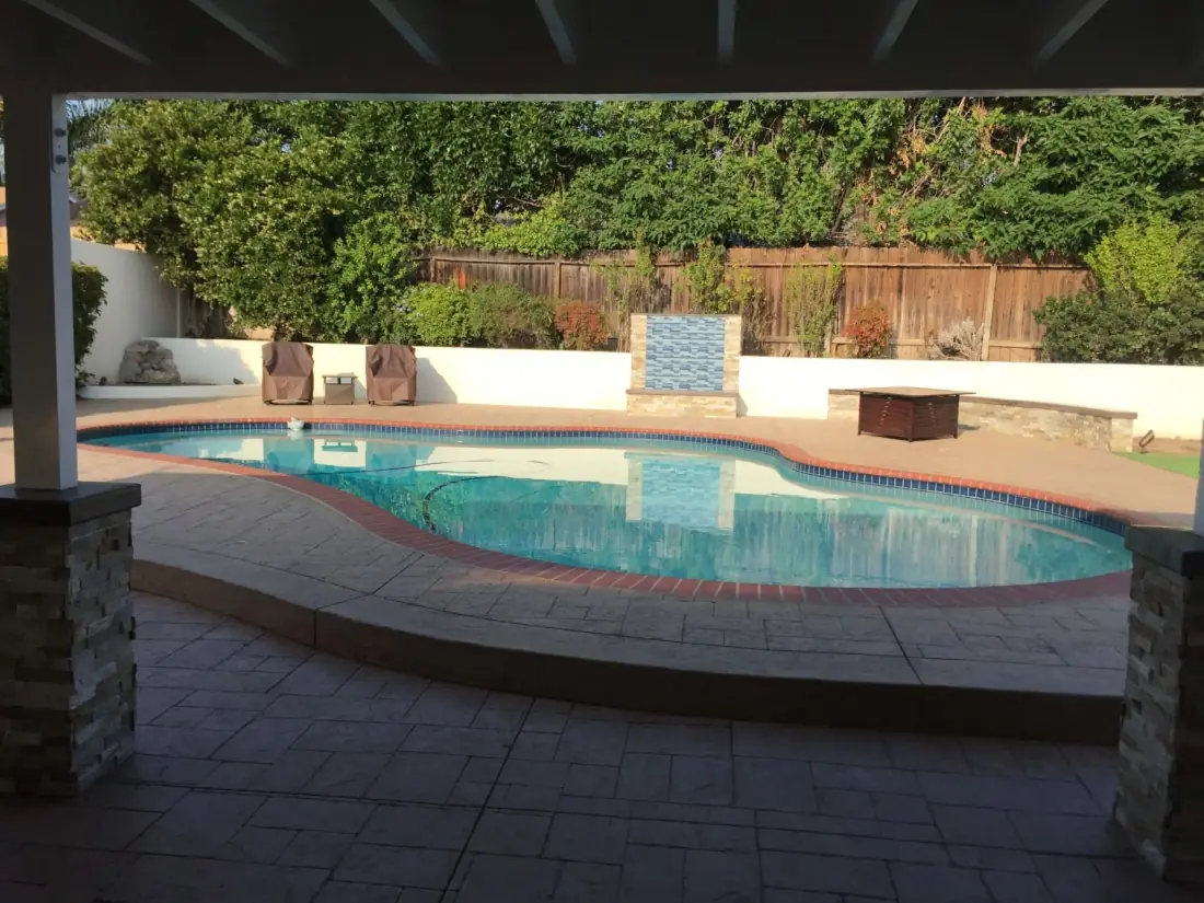 Northridge 2 Kidney-shaped pool with a stamped concrete deck, a tile water feature and a covered patio