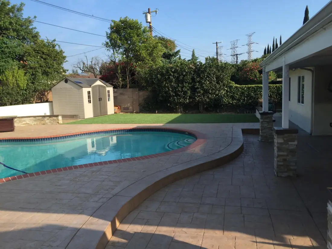 Northridge 1 Kidney-shaped pool with a stamped concrete deck and red brick coping