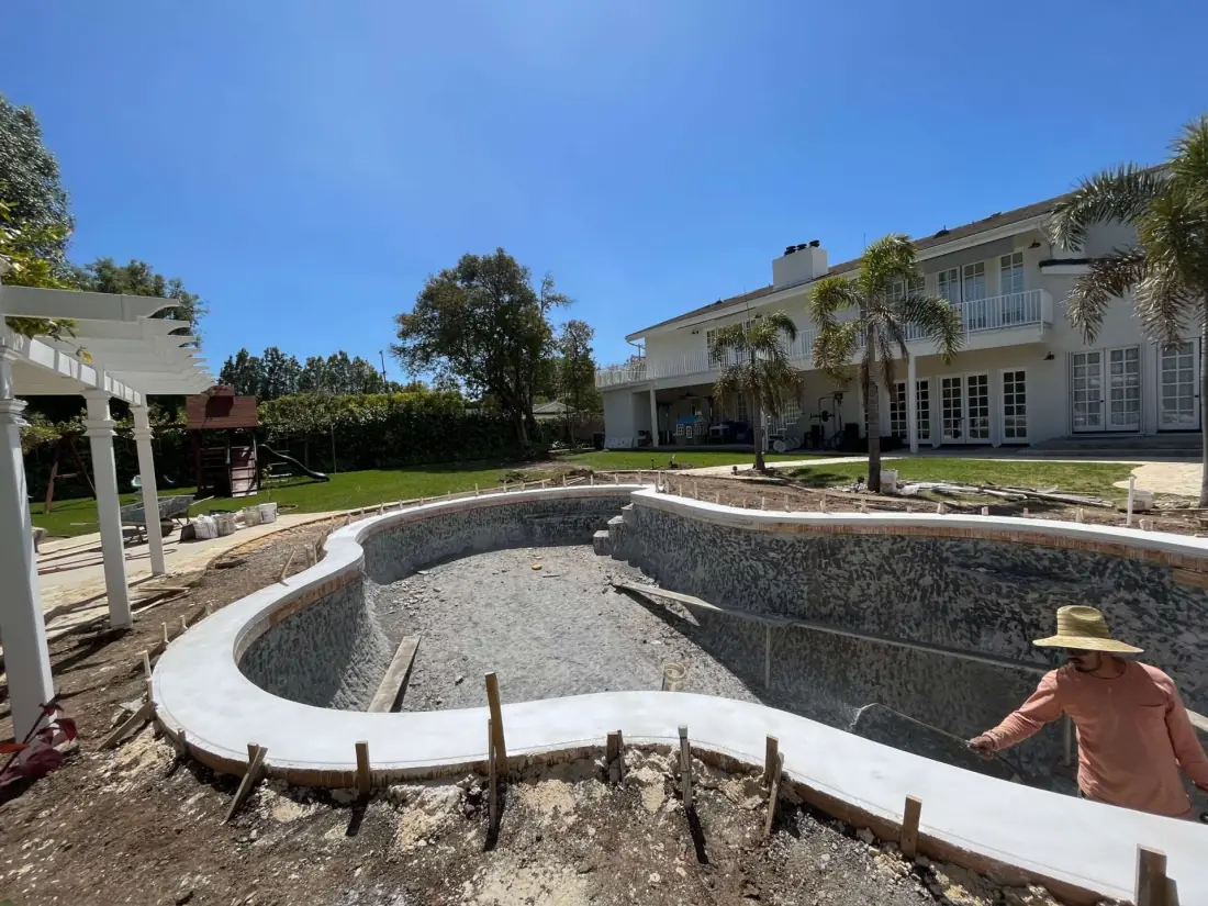 New concrete coping being formed around a stripped kidney-shaped pool