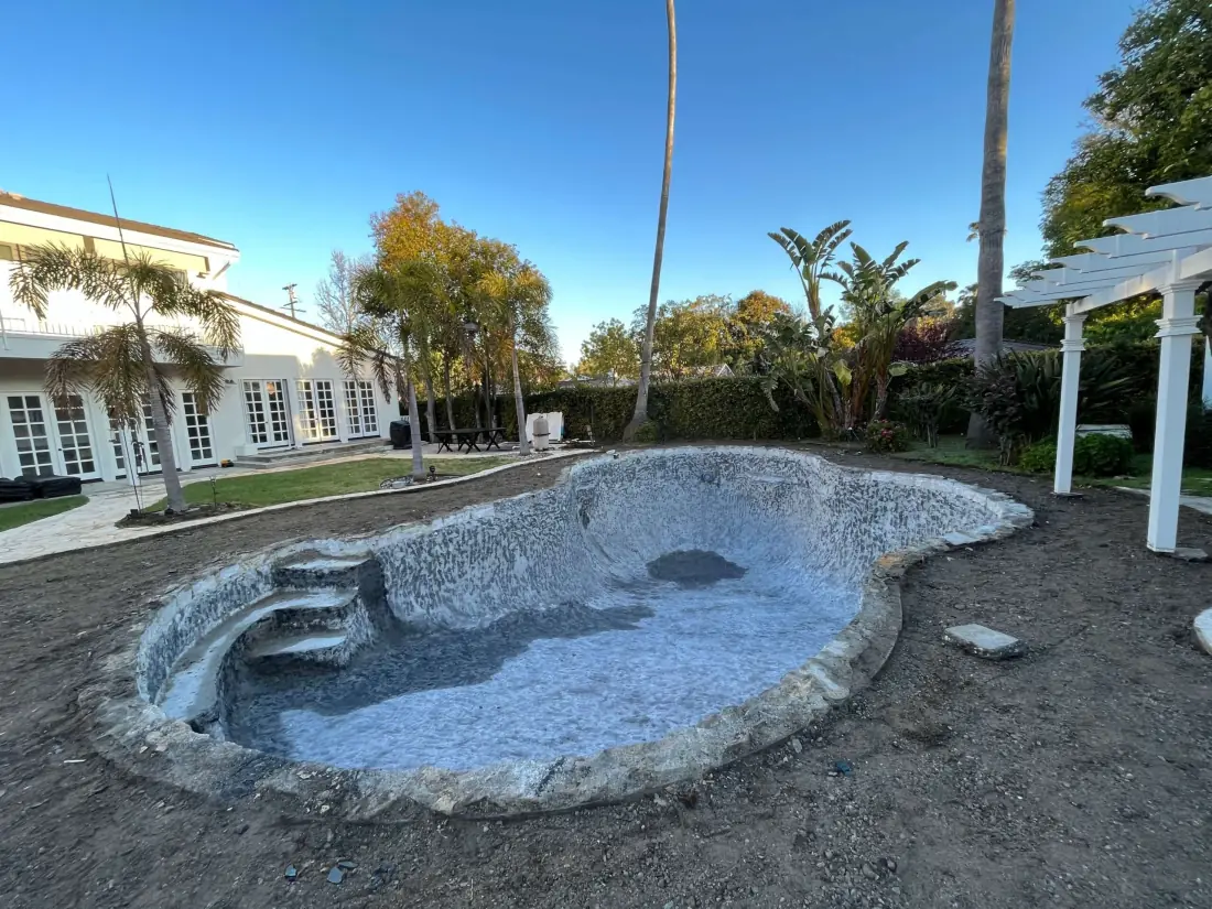Kidney-shaped pool drained and stripped of its old finish before resurfacing