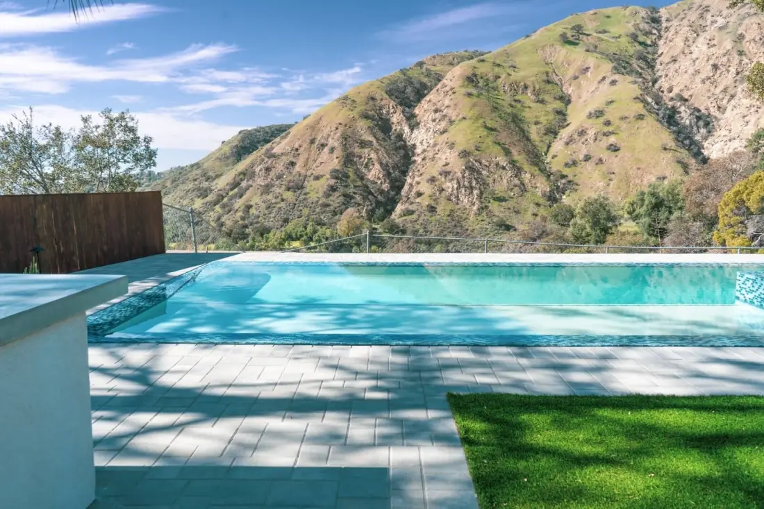 Finished pool with a paver deck and turf set against the mountains