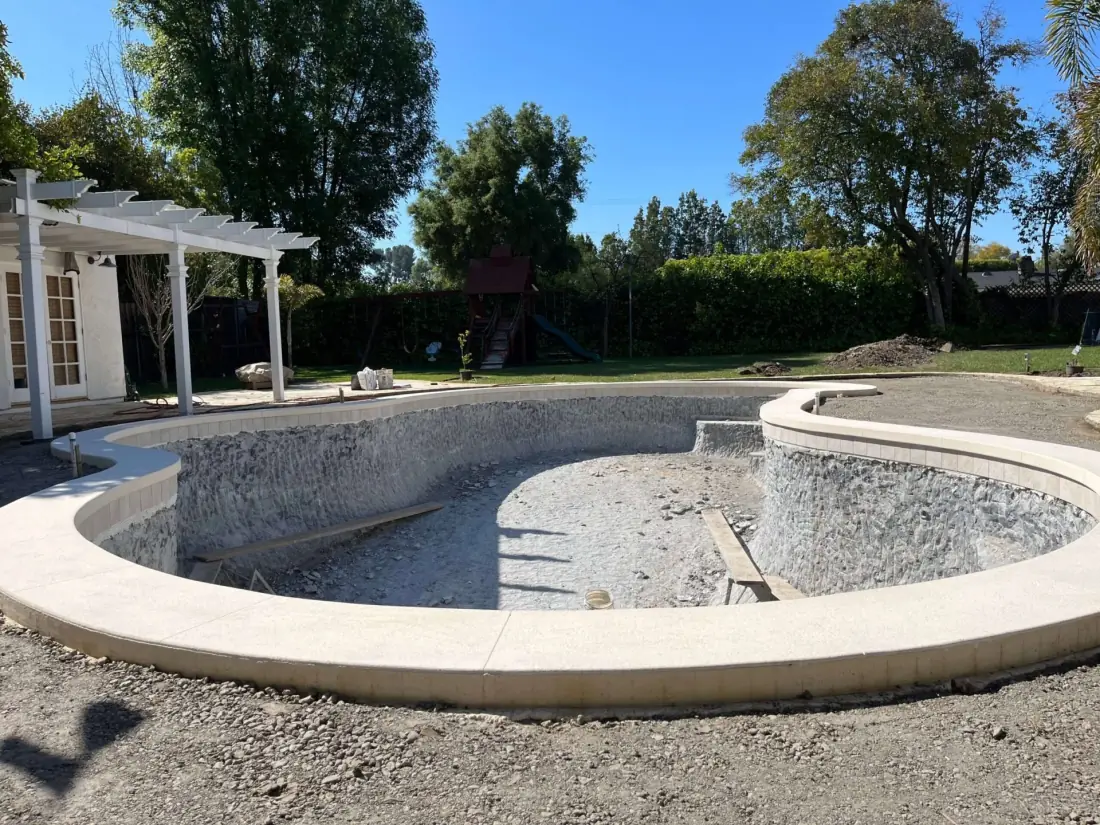 New precast coping set around a stripped pool shell during a renovation