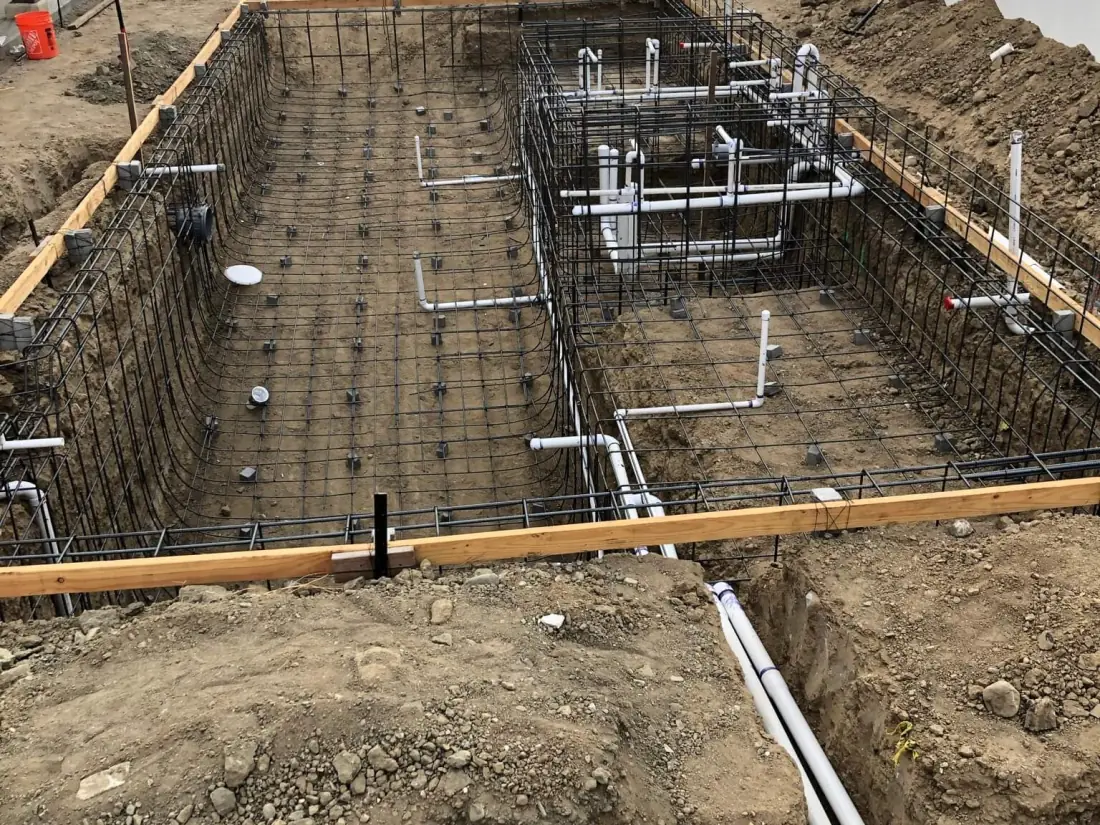 PVC pool pipes laid in a trench and through the rebar of a pool excavation
