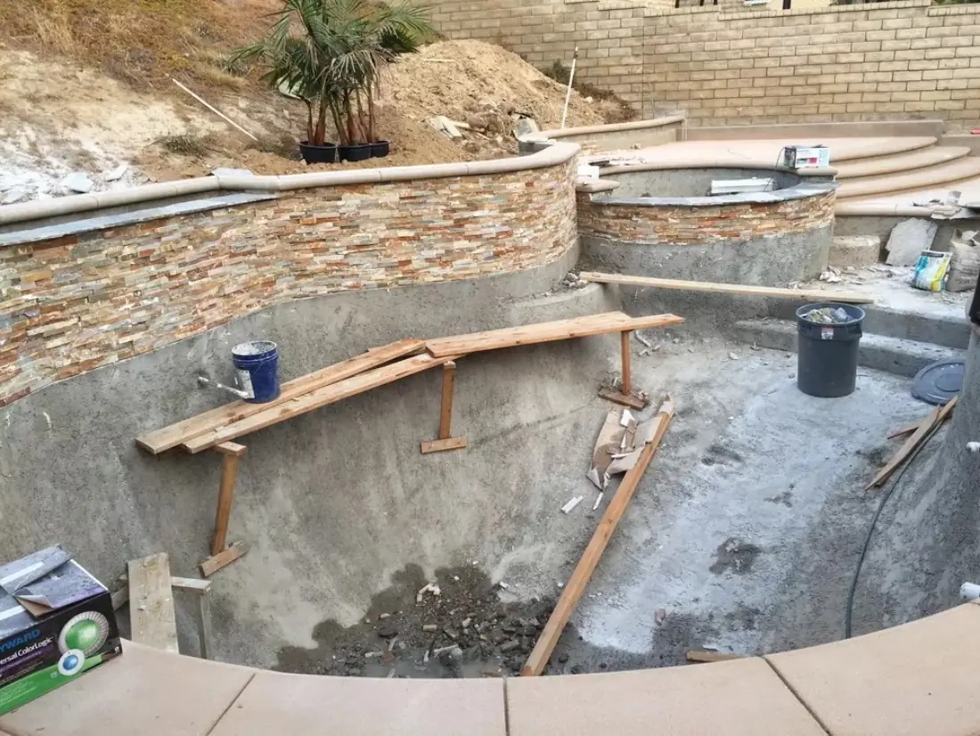 Valley Village 2 Pool shell with stacked-stone veneer being set on the raised spa wall