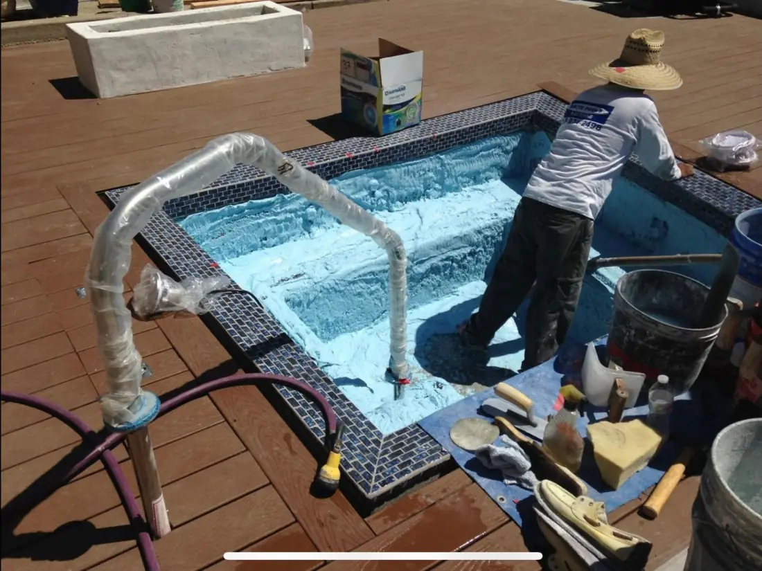 For Designers, Landscape Architects and Developers 1 Tile setter installing blue glass mosaic tile around a spa set into a wood deck