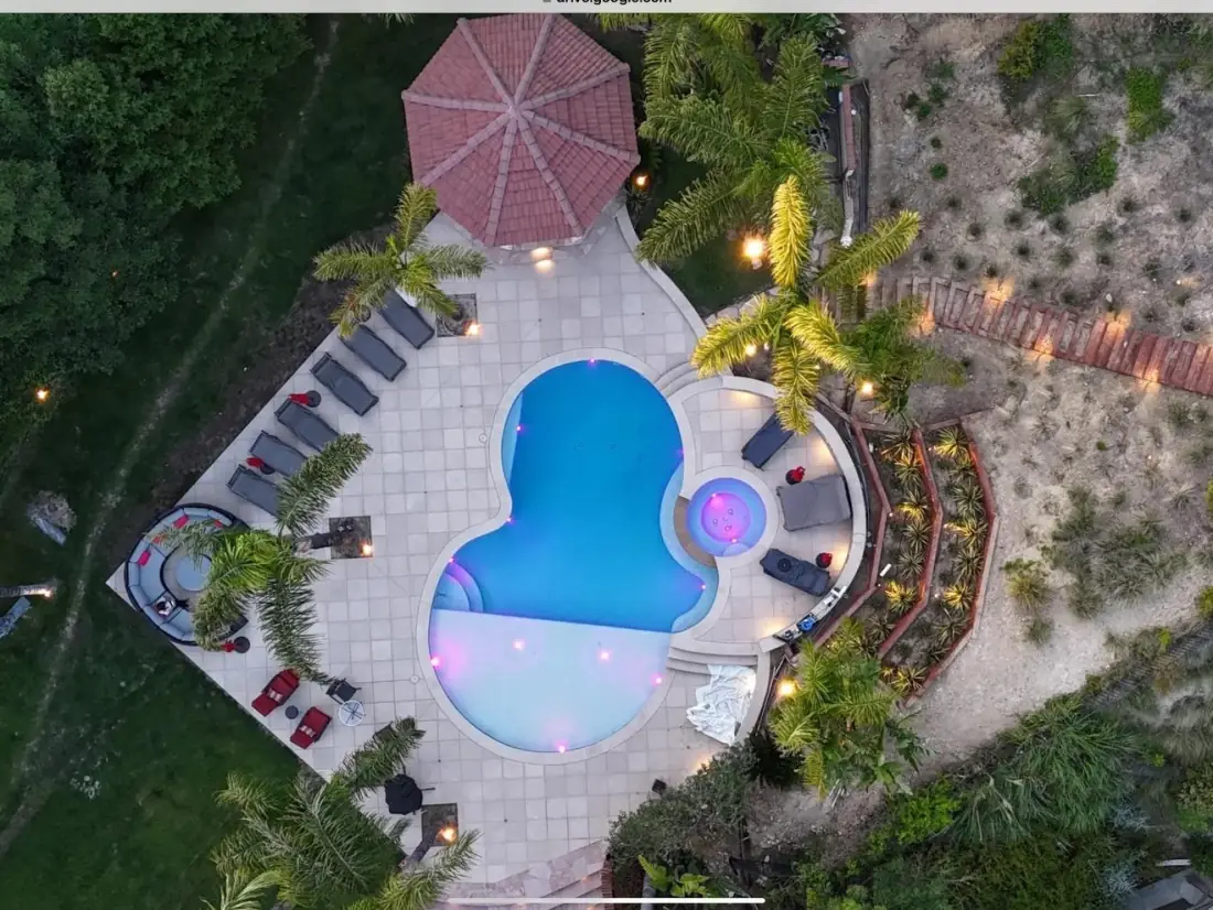 Trade Partners and Referral Program 1 Aerial view of a lit pool and spa at dusk with a gazebo and lounge chairs