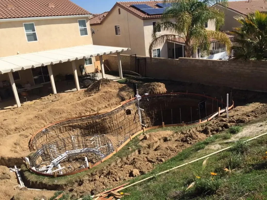 Rebar framing for a freeform pool and spa in a backyard excavation