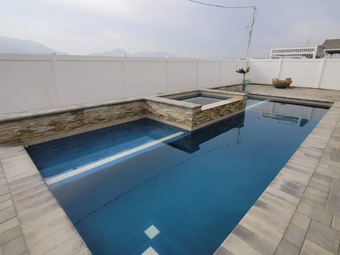 Westlake Village 1 Rectangular pool with a dark finish, paver deck and stacked-stone raised spa