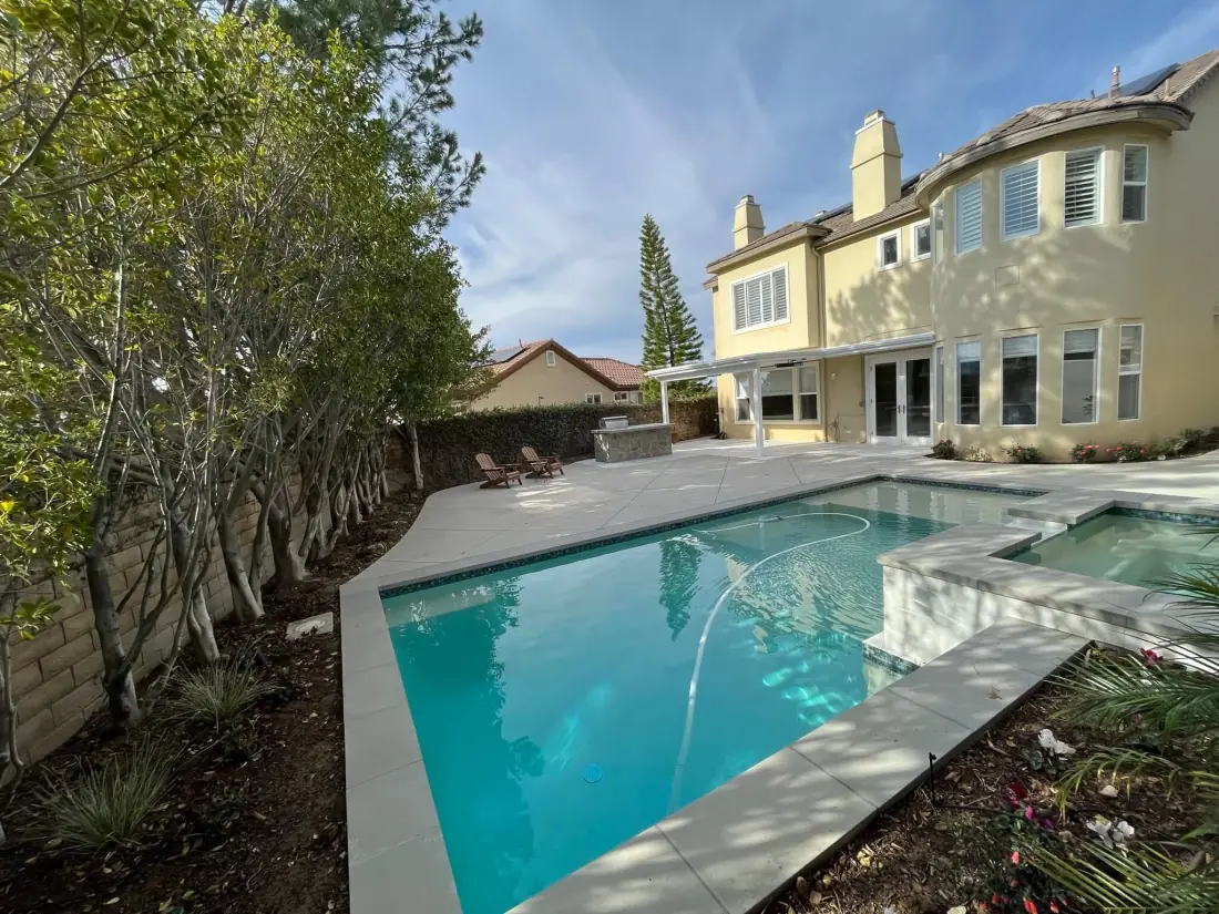 Oak Park 2 Rectangular pool with a sheer descent spilling from a raised spa, with a concrete deck
