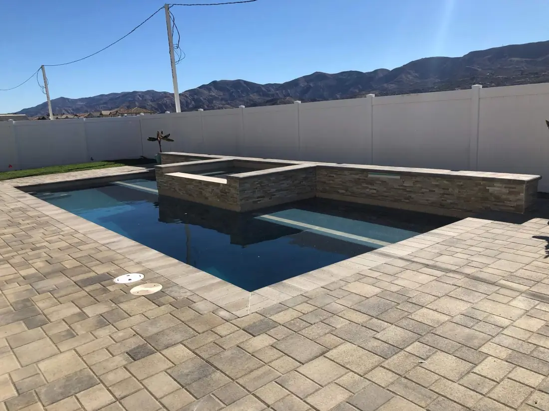 Chatsworth 1 Rectangular pool with a stacked-stone raised spa and paver deck against the mountains