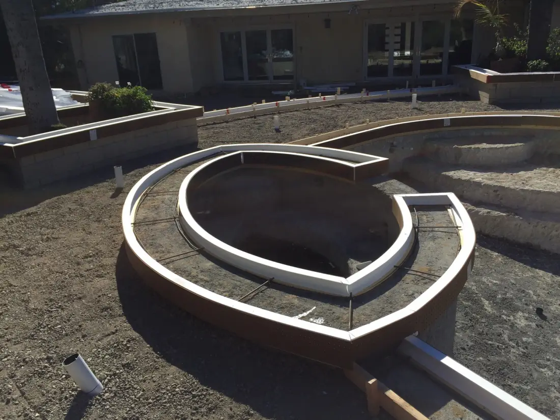 Wood forms for a new round spa and pool in a backyard excavation